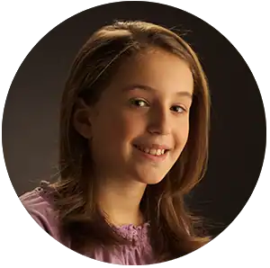 Young girl with hearing aid smiling, promoting hearing health services.