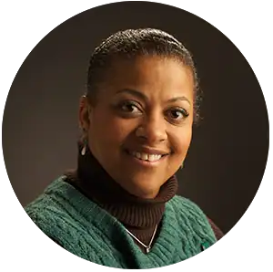 Hearing specialist smiling, wearing green sweater, at Hart Hearing & Balance Centers.